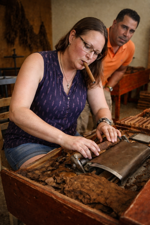 Visitor learning traditional cigar rolling technique with expert guidance at Don Anibal Trujillo boutique factory workshop